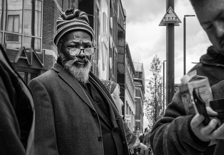 20230415-IMG_5428-Edit A black and white photograph of a man looking at his phone.