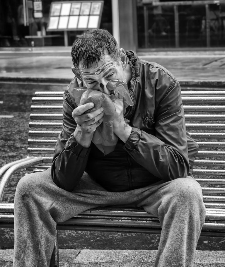 20230708-IMG_7017-Edit A man sitting on a bench taking drugs.