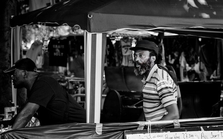 A man in a hat is standing under a tent.