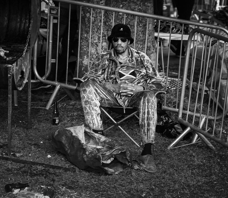 A man sitting on a chair in front of a fence.