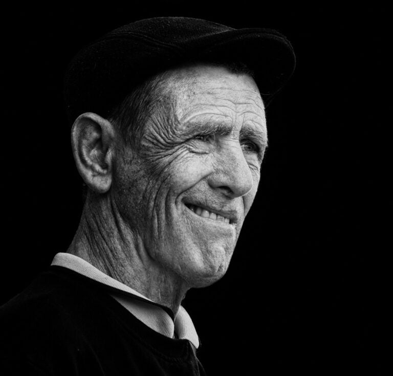 A black and white photo of an old man smiling. A black and white photo of an old man smiling.