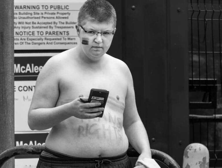 A shirtless man holding a cell phone.