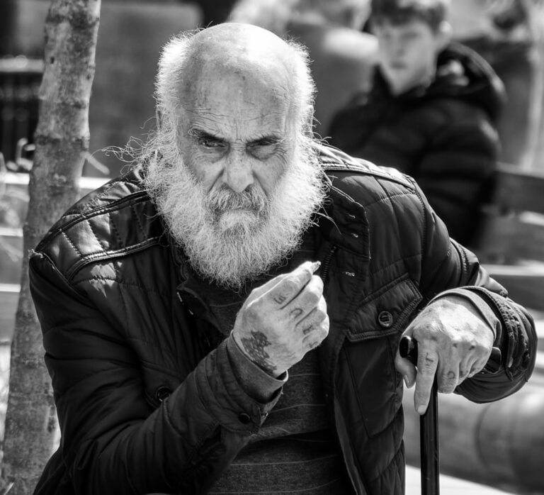 A man with a beard sitting on a bench.