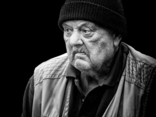 A black and white photo of an old man with a beanie.