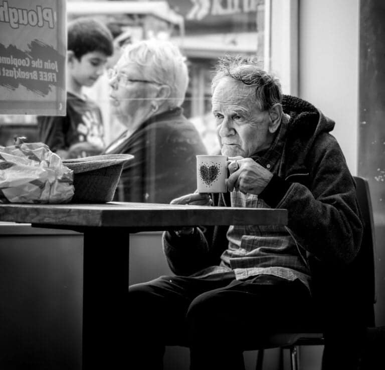 A man sitting at a table with a cup of coffee.