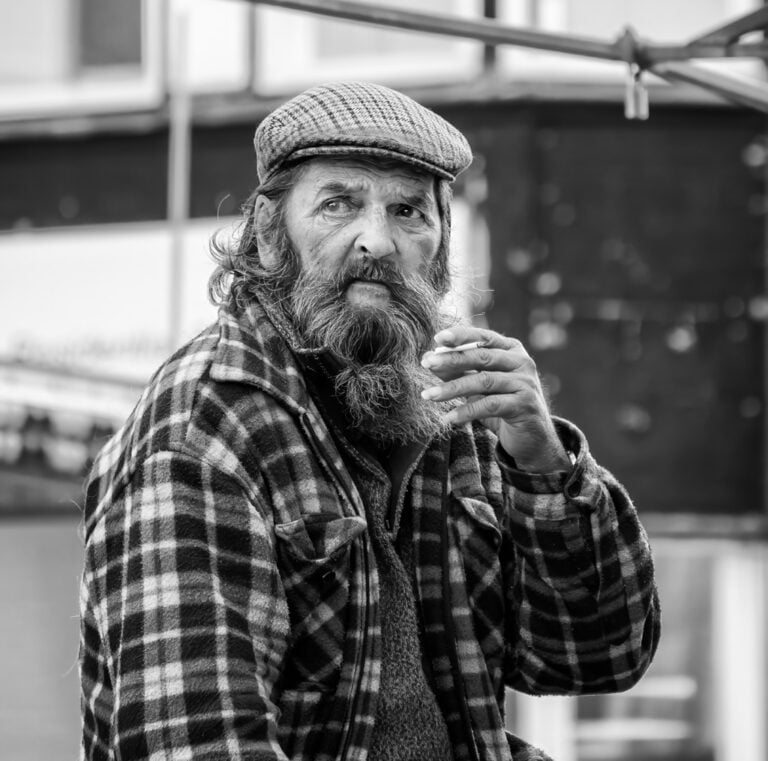 A man with a beard smoking a cigarette.