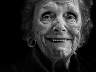 A black and white photo of an old woman smiling.