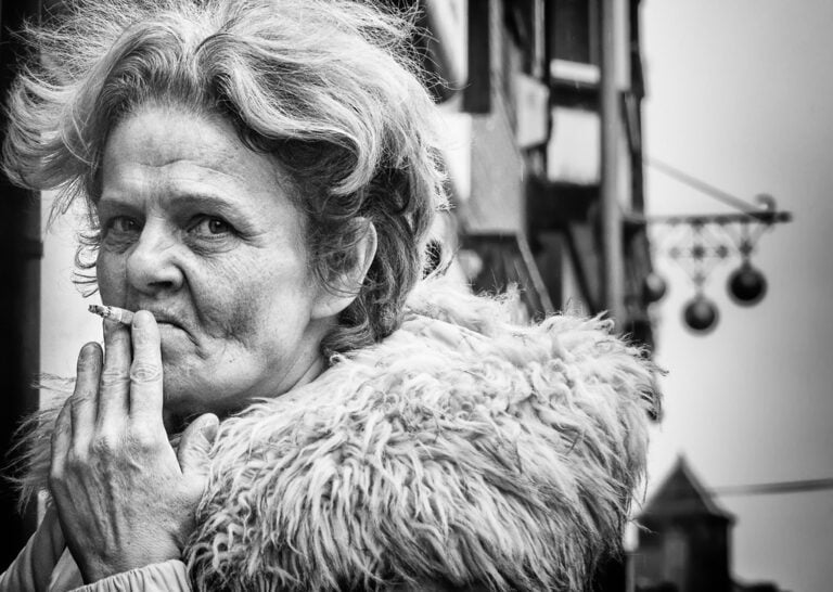 A black and white photo of an old woman smoking a cigarette.