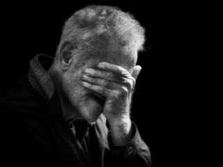 Black and white photo of a man covering his face.