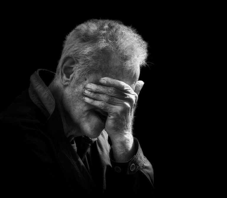 Black and white photo of a man covering his face. Black and white photo of a man covering his face.