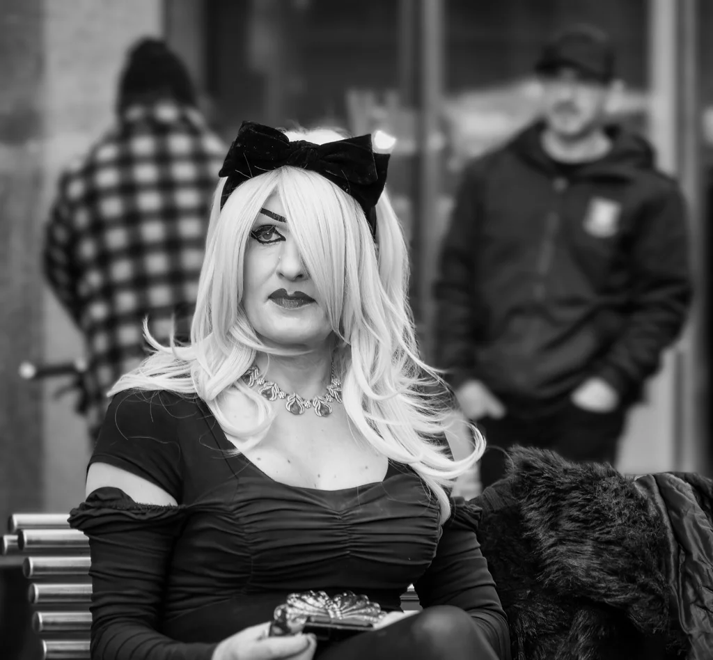 A black and white photo of a woman sitting on a bench.