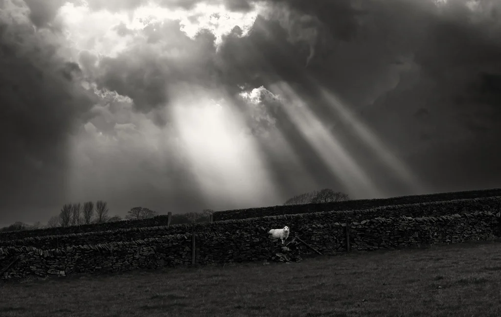 A black and white photo of a stormy sky over a field.
