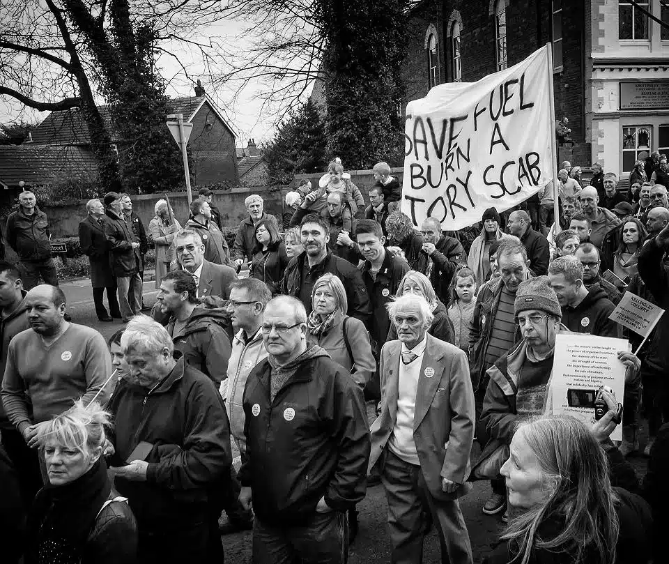 A black and white photo of a group of people holding a sign.