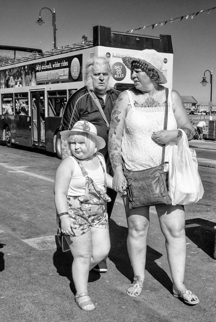 Black and white photograph of a group of people standing in front of a double decker bus.