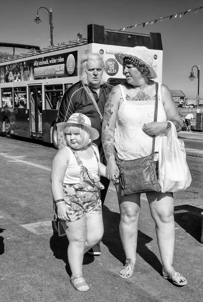 Black and white photograph of a group of people standing in front of a double decker bus.