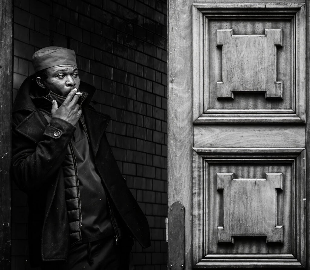 A man smoking a cigarette in front of a door.