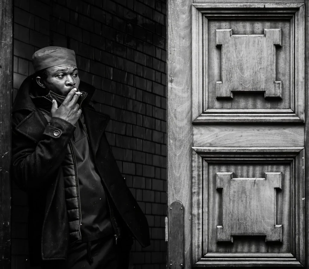 A man smoking a cigarette in front of a door.