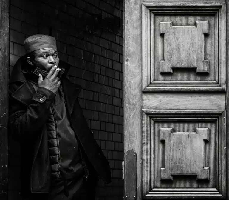 A man smoking a cigarette in front of a door.