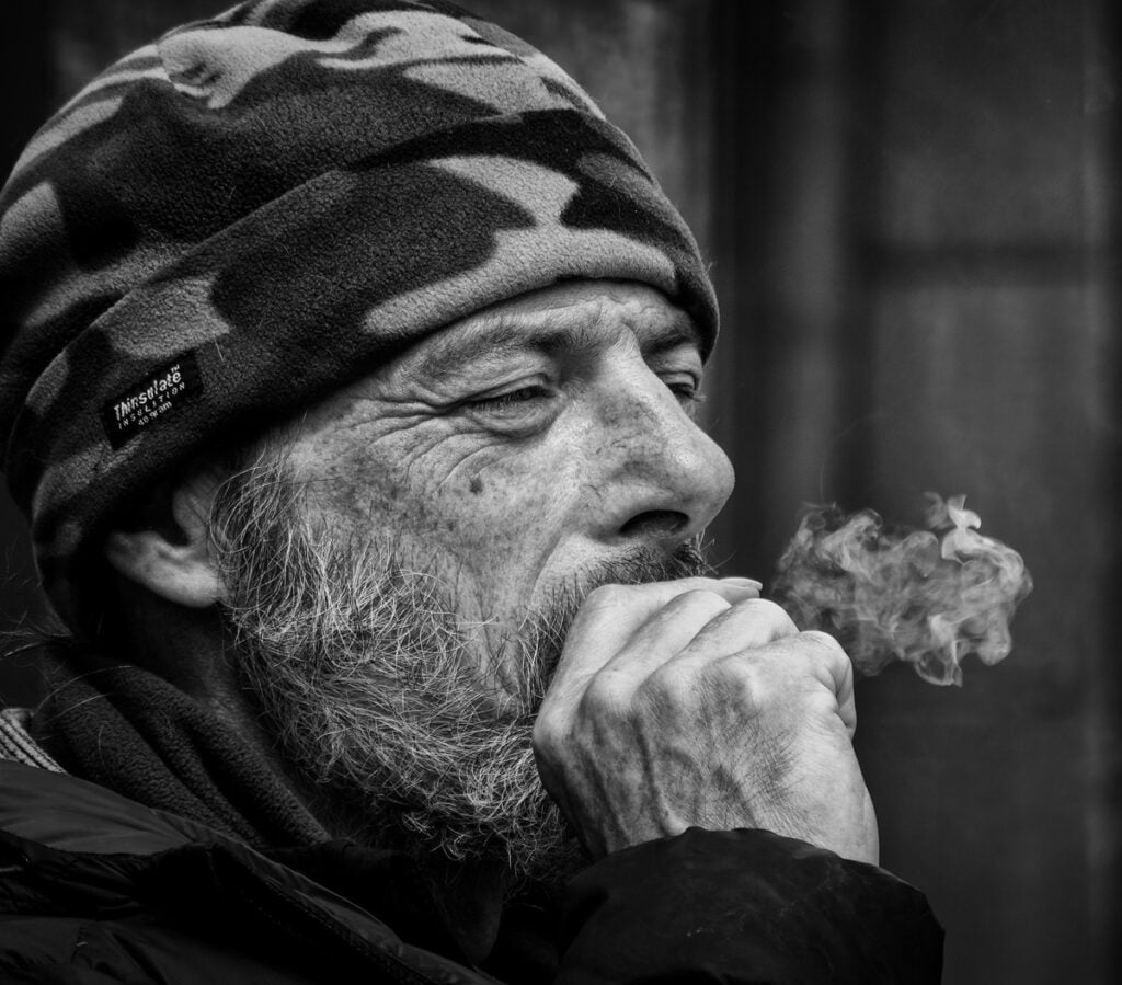 A black and white photo of a man smoking a cigarette.
