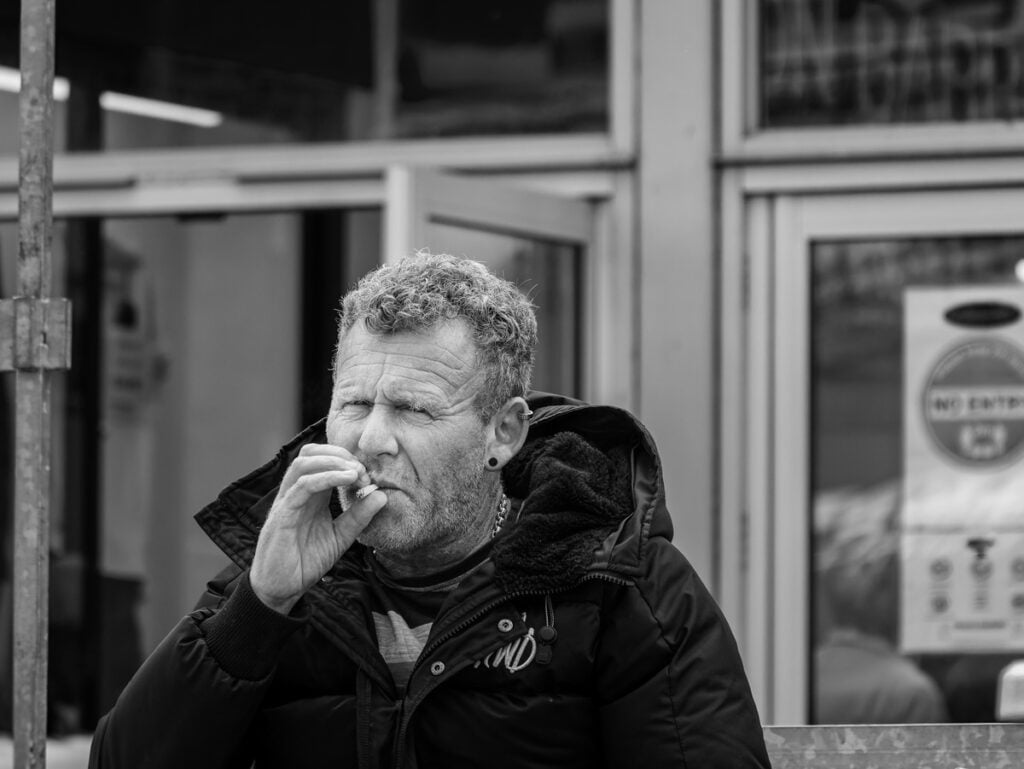 A man sitting on a bench smoking a cigarette.