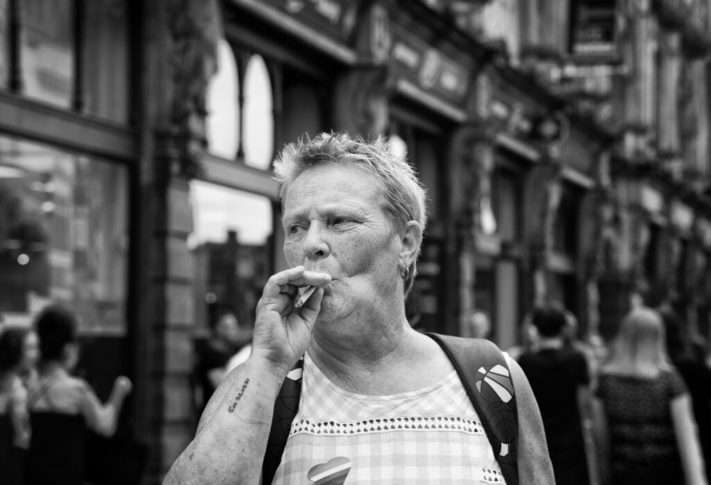 A woman smoking a cigarette on the street.