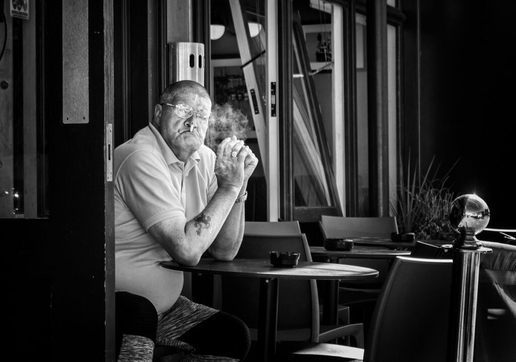 A man sitting at a table smoking a cigarette.