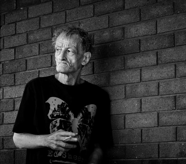 An old man leaning against a brick wall. An old man leaning against a brick wall.