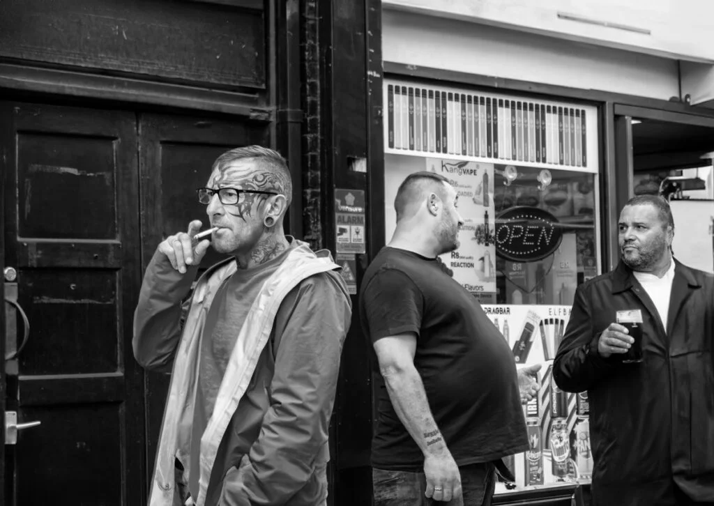 Black and white photograph of a group of men standing in front of a shop.