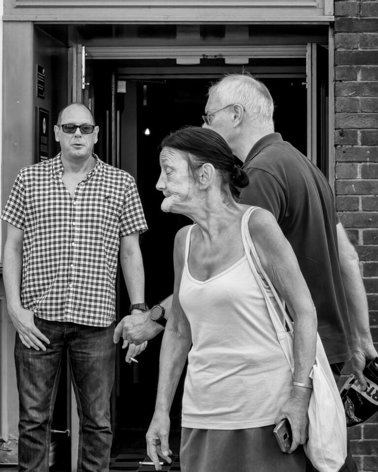 Black and white photograph of a group of people in front of a building. Black and white photograph of a group of people in front of a building.