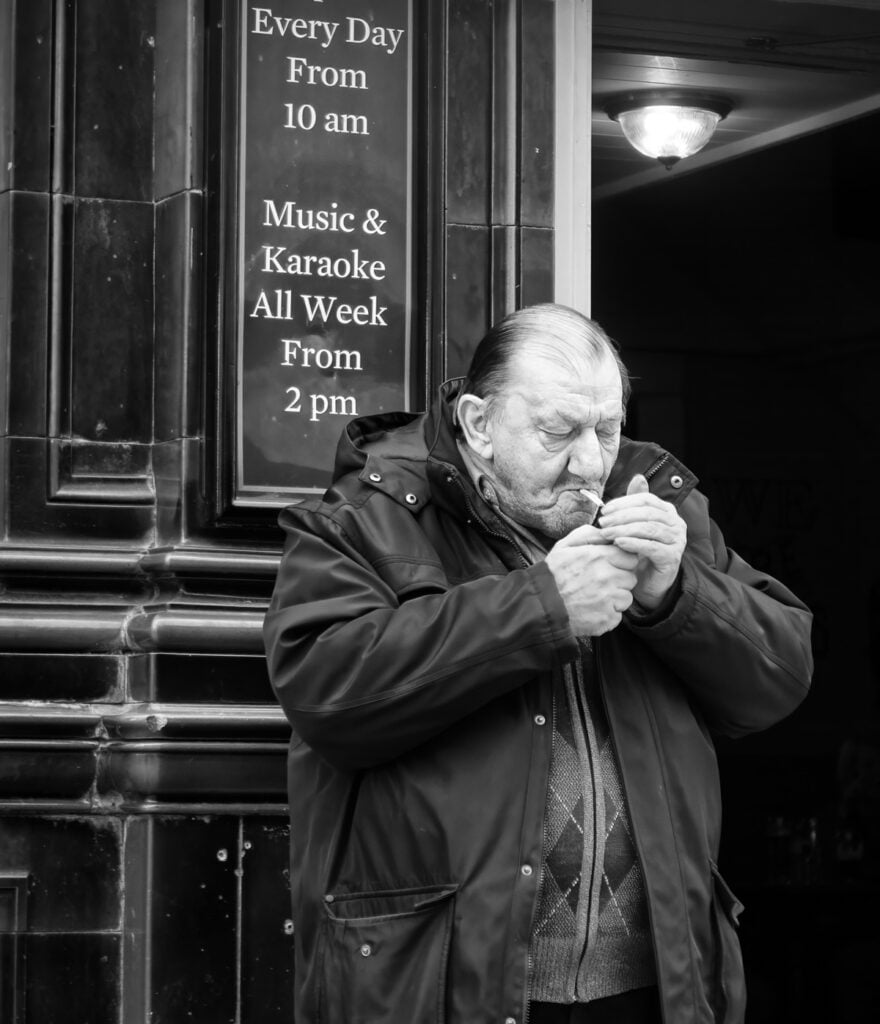A man in a jacket eating a piece of bread.