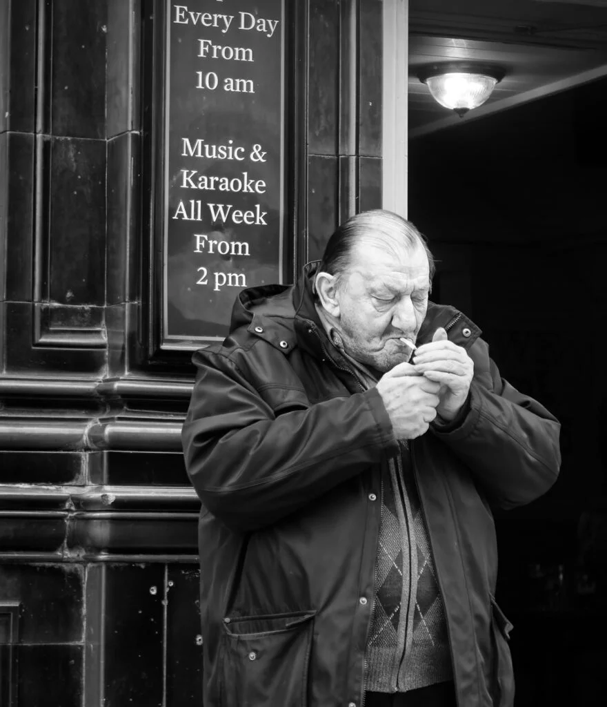 A man in a jacket eating a piece of bread.