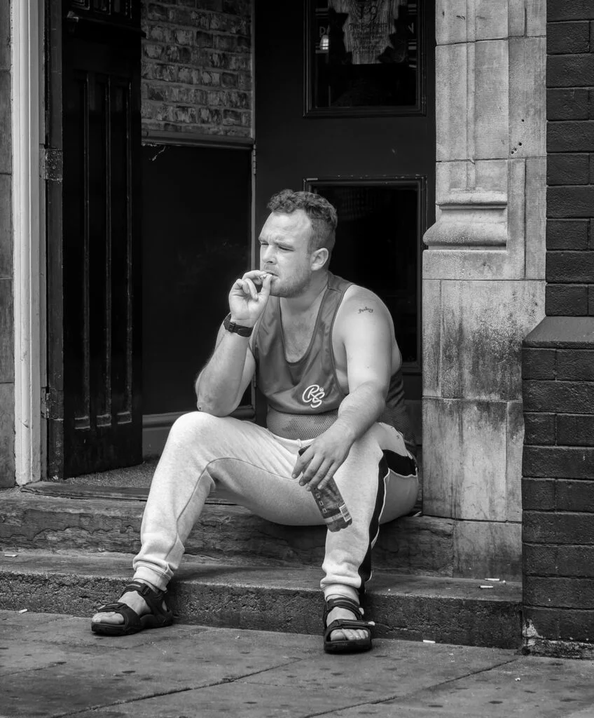 A man sitting on the steps smoking a cigarette.