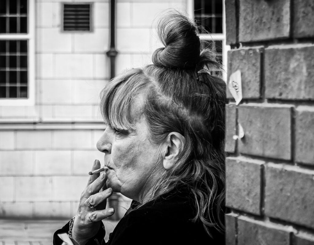 A black and white photo of a woman smoking a cigarette.