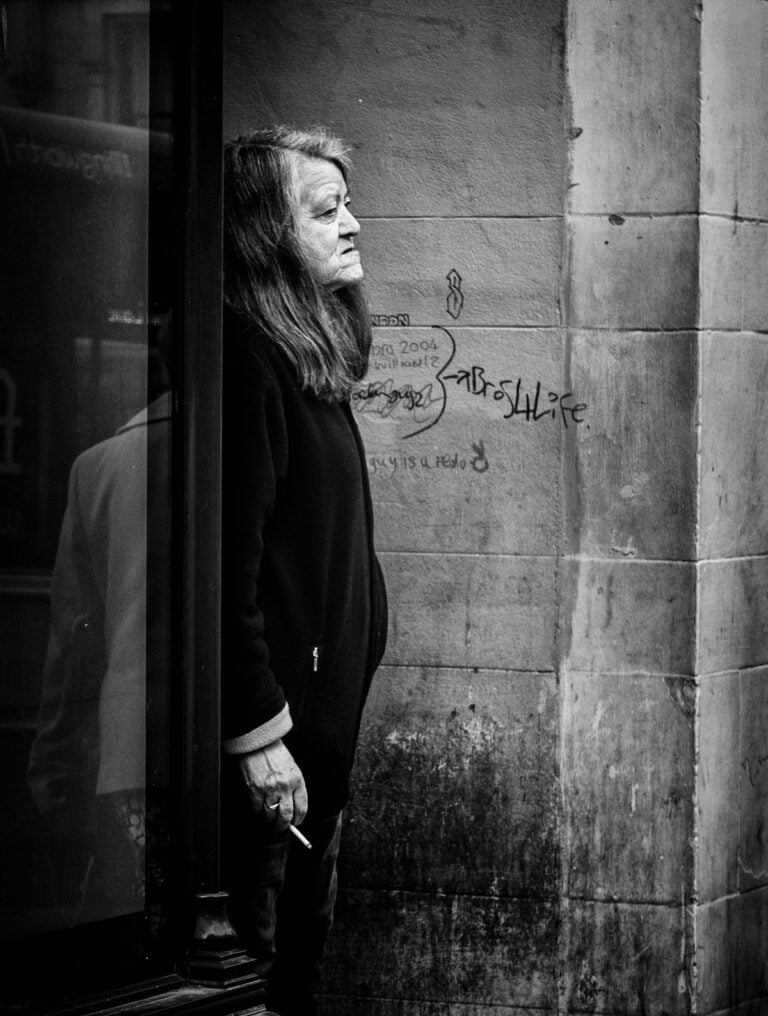A black and white photo of a woman looking out of a window. A black and white photo of a woman looking out of a window.