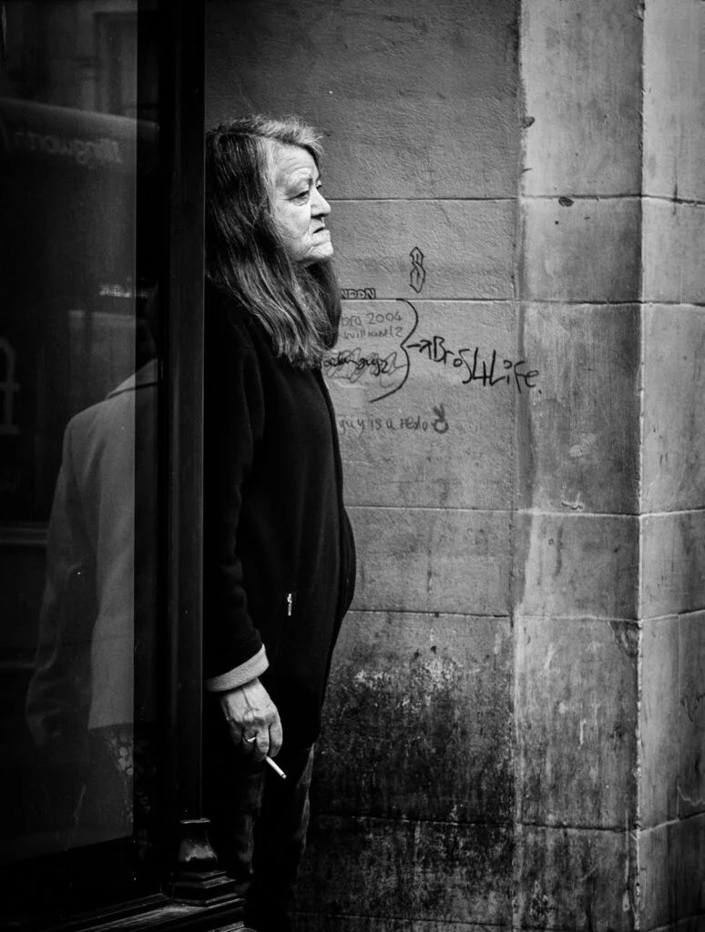 A black and white photo of a woman looking out of a window.