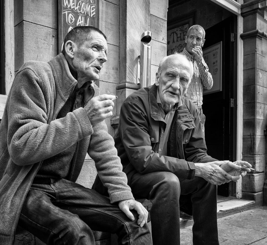 Black and white photograph of two men sitting on a bench.