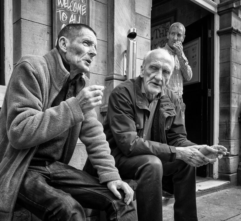 Black and white photograph of two men sitting on a bench. Black and white photograph of two men sitting on a bench.