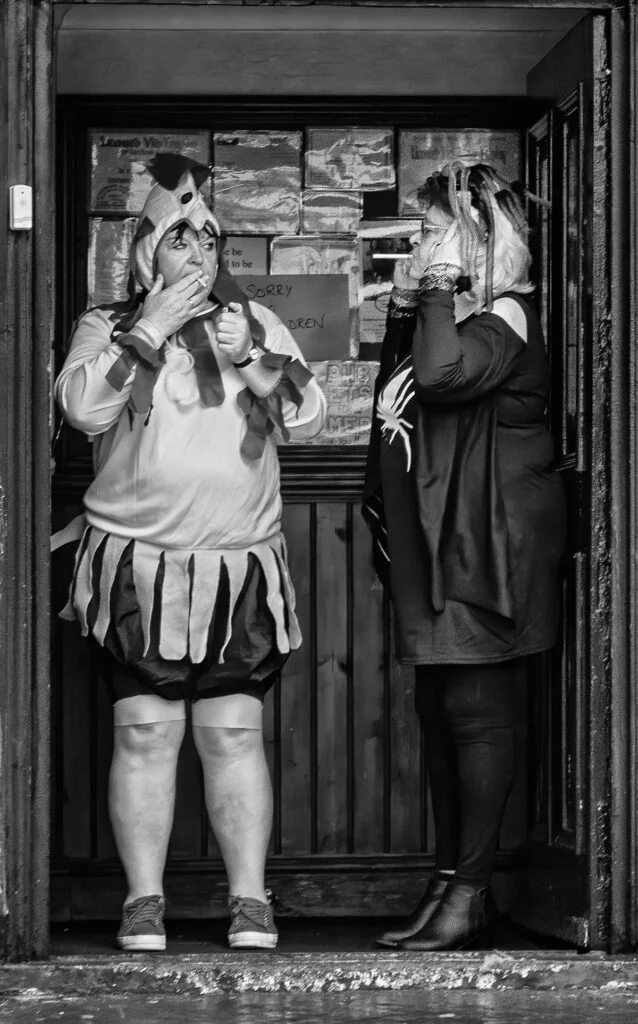 Two women in costumes standing in front of a door.