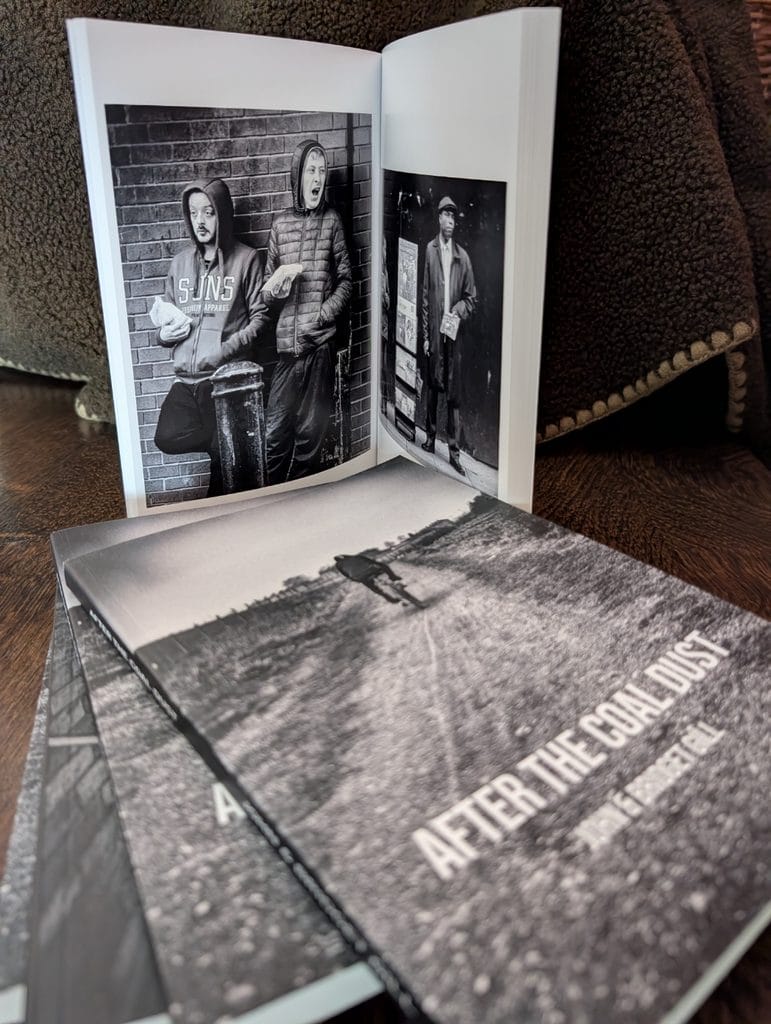 Open copy of After the Coal Dust by John and Bridget Gill showing black-and-white photographs, with more copies including the new A5 edition stacked underneath.